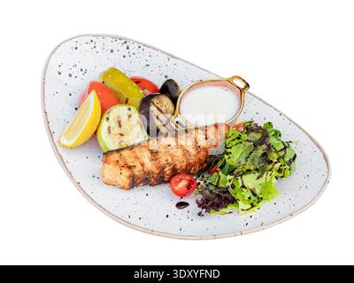 Gegrilltes Fischfilet, serviert mit gegrilltem Gemüse und Sauce auf einem Teller. Isoliert auf weißem Hintergrund, Draufsicht. Stockfoto