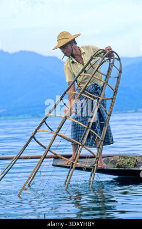 Eine Person fischt am Inle Lake in Myanmar mit traditioneller Bambusausrüstung. Die Aktivität fängt die lokale Lebensweise auf dem Wasser ein. Stockfoto