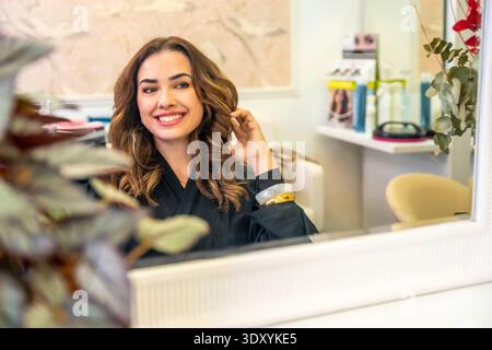 Glückliche Frau, die im Salon frisches Haar erlebt Stockfoto
