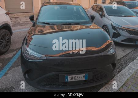 Cremona, Italien - 6. Februar 2026 selbstbewusster junger Profi, der ein Tablet benutzt, in eleganter Freizeitkleidung gekleidet und lächelt, während er in einem modernen Geschäft arbeitet Stockfoto