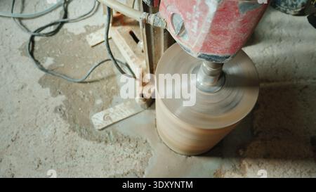Der Baumeister bohrt Löcher in den Betonvorhang für die Verlegung von Lüftungsrohren und Rohrleitungen Stockfoto