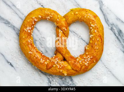 Frisch gebackene hausgemachte Brezel mit grobem Meersalz auf Marmorhintergrund. Deutsche (bayerische) Biervorspeise. Traditionelles herzhaftes Gebäck. Selektiv f Stockfoto