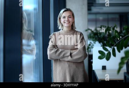 Eine Frau steht vor einem Fenster mit einer Pflanze im Hintergrund Stockfoto