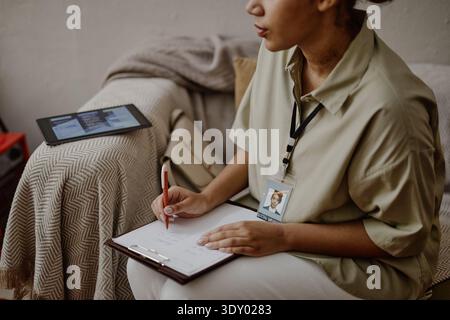 Junge Erwachsene Schwarze Sozialarbeiterin schreibt Notizen während der Kundenberatung Stockfoto