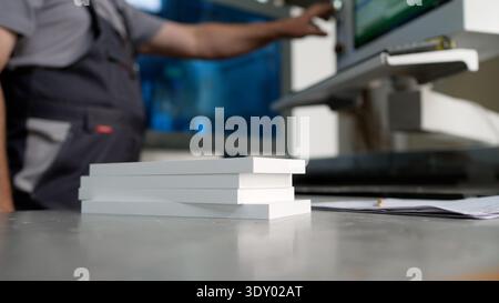 Nahaufnahme von weißen Holzbrettern auf einer Werkbank mit einem Fabrikarbeiter, der Maschinen bedient. Stockfoto
