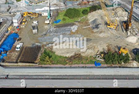 Aus der Vogelperspektive auf Baumaschinen, die auf einer Stelle stehen, wo Erdtöne auf grüne und blaue Planen treffen, Avcılar, İstanbul, Türkiye. Stockfoto