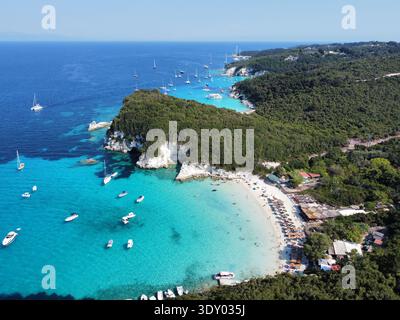 Aus der Vogelperspektive auf das türkisfarbene Meer, das sanft das Ufer eines Strandes küsst, eingerahmt von Klippen und dichten Wäldern, Korfu, Griechenland. Stockfoto