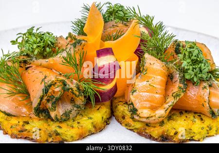 Elegante geräucherte Lachsrosetten auf knuspriger Kartoffelrösti mit Kräutersoße Stockfoto