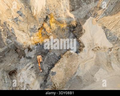 Aus der Vogelperspektive sehen Sie die strukturierten Schichten eines riesigen Steinbruchs, wo Erdtöne auf den metallischen Glanz der Maschinen treffen und tief in die Landschaft eingraben, Miradouro da Stockfoto