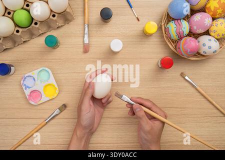 SSTK Ostern. Kreative Hände malen Ostereier mit leuchtenden Farben und künstlerischen Werkzeugen. Stockfoto