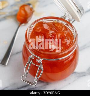 Hausgemachte köstliche süße Marmelade aus weißen Kirschen in einem Glas auf Marmorhintergrund. Ein Leckerbissen für Tee oder eine Füllung für Kuchen. Kirschmarmelade. Berrie Stockfoto