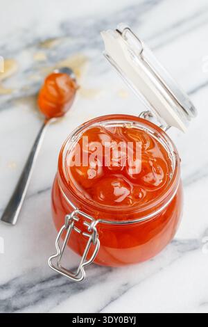 Hausgemachte köstliche süße Marmelade aus weißen Kirschen in einem Glas auf Marmorhintergrund. Ein Leckerbissen für Tee oder eine Füllung für Kuchen. Kirschmarmelade. Berrie Stockfoto