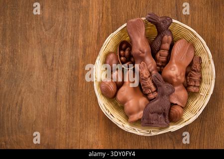 Schokoladen-osterhasen und Eier im Korb auf Holz Stockfoto