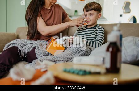Mom besprüht die Nase des Jungen mit Nasenspray Stockfoto