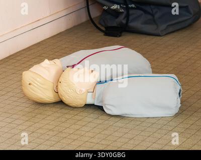 HLW-Trainingspuppen, die während eines ersten-Hilfe-Kurses auf dem Boden liegen und zur Praxis kardiopulmonaler Reanimationstechniken verwendet werden. Stockfoto