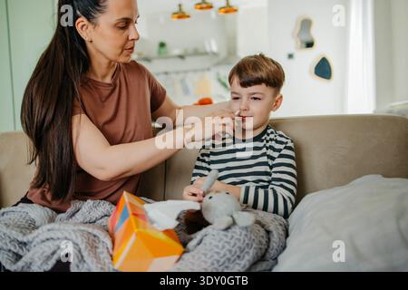 Mom besprüht die Nase des Jungen mit Nasenspray Stockfoto