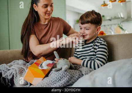 Mom besprüht die Nase des Jungen mit Nasenspray Stockfoto