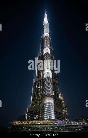 Ein vertikales, flaches Foto des Burj Khalifa in Dubai bei Nacht. Das höchste Gebäude der Welt ist mit hellen weißen architektonischen Leuchten beleuchtet Stockfoto