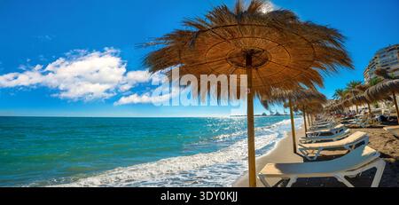 Panoramablick auf den Stadtstrand entlang der Küste mit Strohschirmen in Malaga. Costa del Sol, Andalusien, Spanien Stockfoto