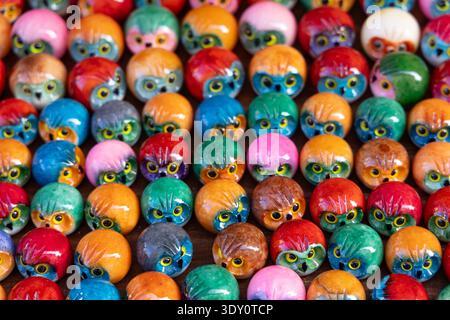 Farbenfrohe, handgefertigte Keramikeule, die in Reihen an einem Souvenirmarkt angeordnet sind, lebendige dekorative Kunsthandwerksobjekte. Stockfoto