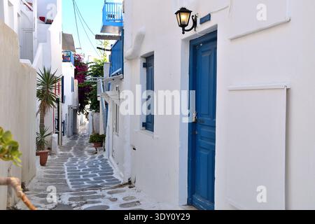 Weiße Gasse mit blauer Tür und Balkon in Mykonos, Griechenland Stockfoto