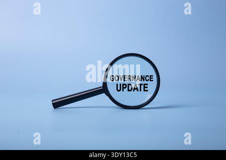 Vergrößerungsglas mit Fokus auf die Wörter Governance Update auf blauem Hintergrund Stockfoto