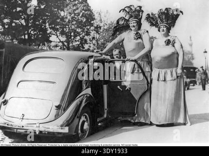 Menschen, die von Gigantismus betroffen sind, können aufgrund einer Überproduktion von Wachstumshormon, in der Regel durch eine Hypophysenerkrankung, bis die Knochenwachstumsplatten in späten Teenagern schließen, zu außergewöhnlichen Höhen wachsen. Dieses auffällige Foto, das 1936 aufgenommen wurde, zeigt zwei außergewöhnlich große Frauen: Anna mit einer Größe von etwa 234 cm und Norah mit etwa 220 cm. Sie werden neben einem Standardauto gezeigt, wobei ein Mann mit durchschnittlicher Größe für dramatische Skalen enthalten ist – der Größenunterschied ist sofort auffallend. Die Originalunterschrift beschreibt sie als eine beliebte Attraktion zu dieser Zeit, fast sicher p Stockfoto