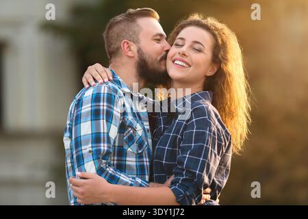 Ein Paar genießt einen zärtlichen Moment im Freien, während er Lächeln und Zuneigung im Abendlicht teilt Stockfoto