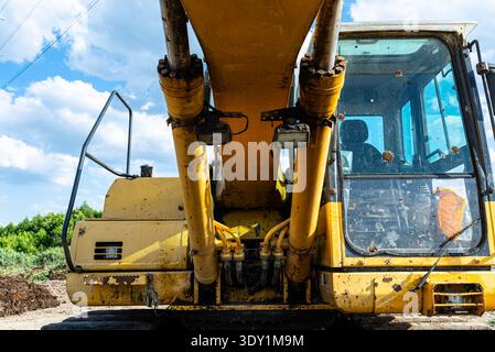 Gelber Hydraulikbagger, der auf einer Baustelle unter blauem Himmel betrieben wird Stockfoto