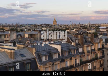 Blick auf die Dächer, die im sanften Glanz der untergehenden Sonne getaucht sind, eine goldene Kuppel, die die Pariser Skyline am ruhigen Abend durchsetzt, Paris, Île-de-Fra Stockfoto