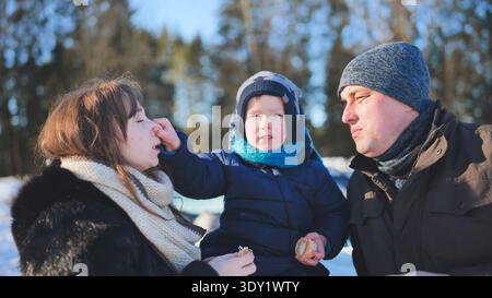 Glückliche Familie, die an einem Wintertag in einem schneebedeckten Wald gemeinsame Zeit verbringt und die Gesellschaft des anderen genießt Stockfoto