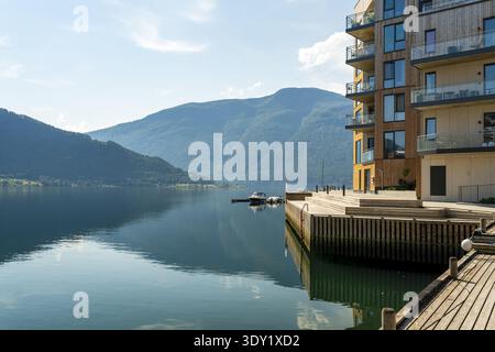 Blick auf das ruhige Wasser spiegelt die majestätischen Berge unter einem ruhigen Himmel wider, mit moderner Architektur, die einen Hauch von Eleganz verleiht, Sogndal, Vestland, Norw Stockfoto