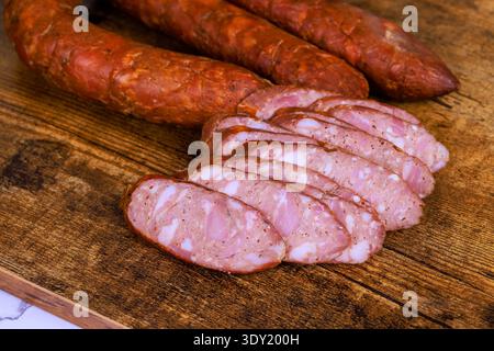 Aufgeschnittene Wurststücke liegen auf Holzbrett und ganze Würstchen in der Nähe in der Küche. Stockfoto