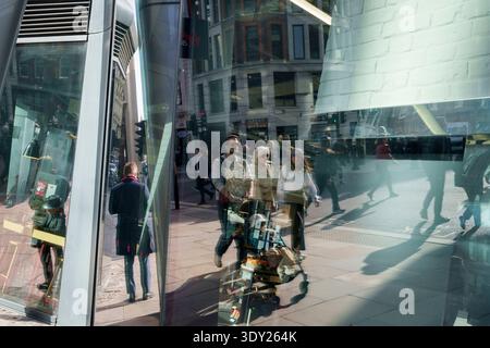 Fußgänger und Passanten spazieren am 5. März 2026 in London, England, durch ein Stadtbild aus Licht, Schatten und Glasreflexionen. Stockfoto