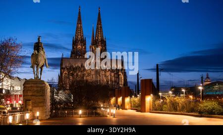 Köln, Deutschland - 18. Dezember 2026: Blick auf den Kölner Dom und die Reiterstatue zur blauen Stunde mit beleuchteter Promenade Stockfoto