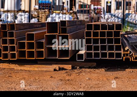 Gestapelte quadratische Stahlprofile mit industriellem Baumaterial auf einer Baustelle Stockfoto