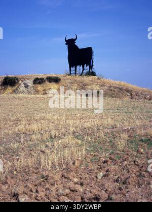 Die legendäre Silhouette des Osborne-Stiers steht auf einem trockenen, ländlichen Hügel in Andalusien, Spanien, unter einem klaren blauen Himmel. Stockfoto