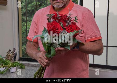 Reifer Erwachsener mit einem wunderschönen Blumenstrauß roter Rosen, der Liebe und Romantik symbolisiert Stockfoto