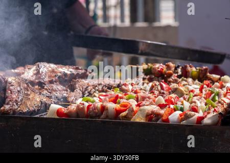 Köstliche gegrillte Fleisch- und Gemüsespieße auf dem Grill im Freien. Stockfoto