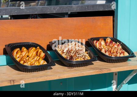 Verschiedene Street Food-Platten auf einer Holztheke an einem pulsierenden Außenstand. Stockfoto