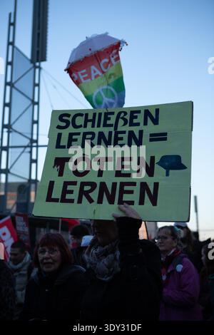 Leipzig, Sachsen, Deutschland. März 2026. Ein Demonstrant hält während einer Demonstration gegen den Wehrdienst in Leipzig ein Schild mit der Aufschrift „SchieÃŸen lernen = TÃ¶ten lernen“, mit einer Regenbogenfahne „Frieden“ über der Menge. (Kreditbild: © Maria Castro/ZUMA Press Wire) NUR REDAKTIONELLE VERWENDUNG! Nicht für kommerzielle ZWECKE! Stockfoto