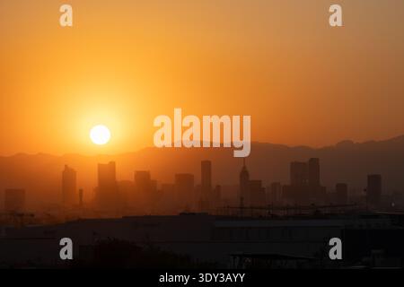 Goldener Sonnenuntergang über der Silhouette der Skyline von Mexiko-Stadt mit Torre Latinoamericana und fernen Bergen im trüben Orangenlicht, Mexiko. Stockfoto