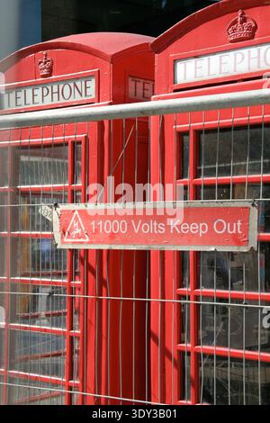 Die 11.000 Volt Telefonkabine: Nahaufnahme der roten Londoner Telefonboxen hinter einem Hochspannungs-Warnschild (ca. 2006) Stockfoto