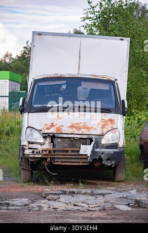Verlassener rostiger weißer Van-Truck, der auf einer kaputten Straße steht Stockfoto
