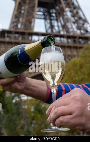 Ausgießen und Trinken von französischem Sekt aus Tulpenglas mit Blick auf die Straßen, Gebäude und Türme von Paris, Hochzeitsveranstaltung in Paris Stockfoto