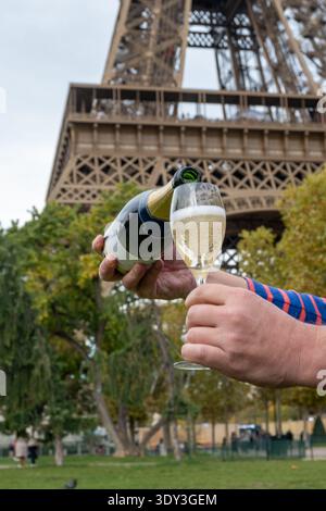 Ausgießen und Trinken von französischem Sekt aus Tulpenglas mit Blick auf die Straßen, Gebäude und Türme von Paris, Hochzeitsveranstaltung in Paris Stockfoto