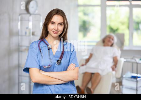 Lächelnde Oberärztin in Uniform mit einer Patientin, die in der Klinik liegt. Stockfoto