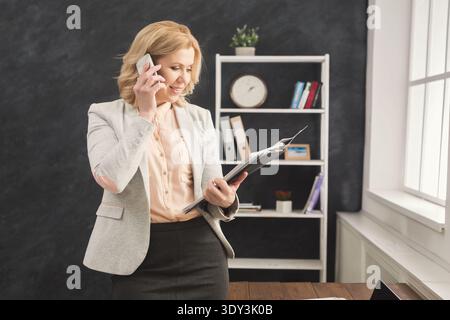 Erfolgreiche Geschäftsfrau auf der Arbeit, die am Telefon spricht Stockfoto