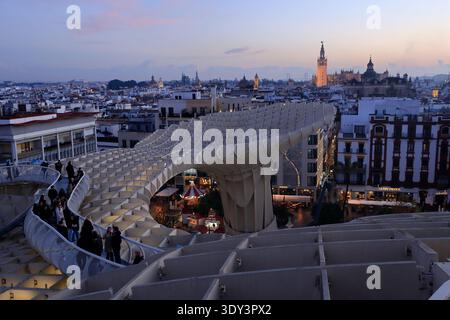 Der Blick in die Dämmerung auf die Besucher auf Setas de Sevilla mit dem La Giralda Turm der Kathedrale von Sevilla im Hintergrund. Sevilla, Spaiin Stockfoto