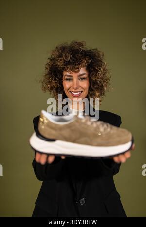 Eine Frau posiert und hält ein Paar Turnschuhe in der Hand Stockfoto